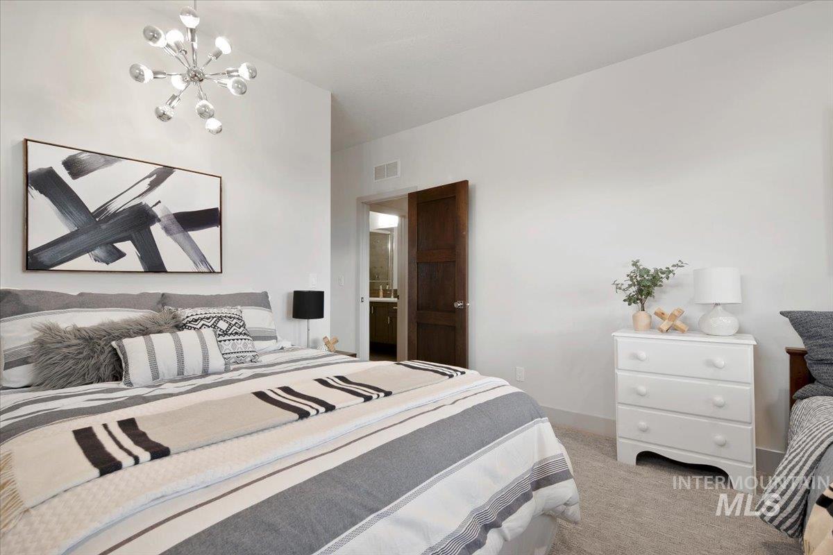 Carpeted bedroom featuring a chandelier and baseboards