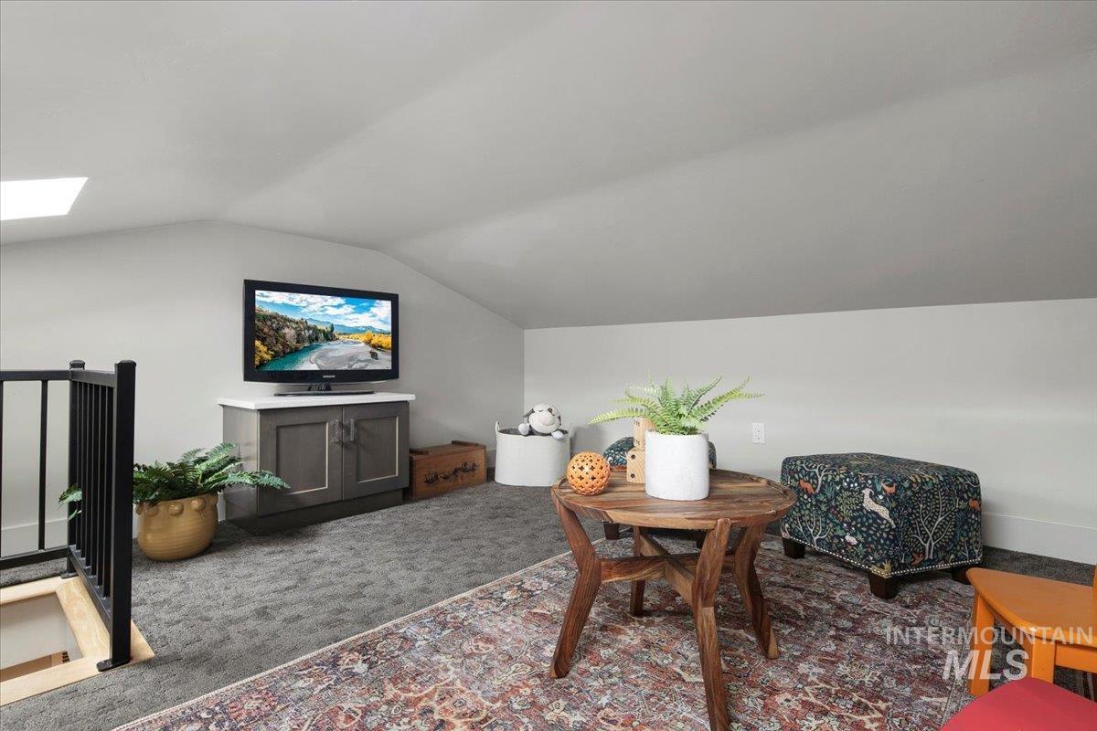 Sitting room featuring a skylight, carpet flooring, and vaulted ceiling
