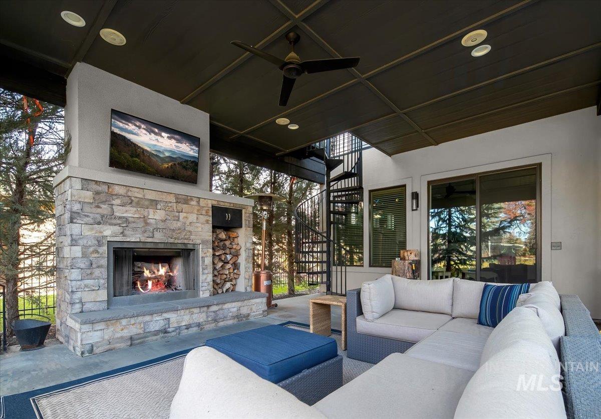 View of patio with ceiling fan, stairs, and an outdoor living space with a fireplace