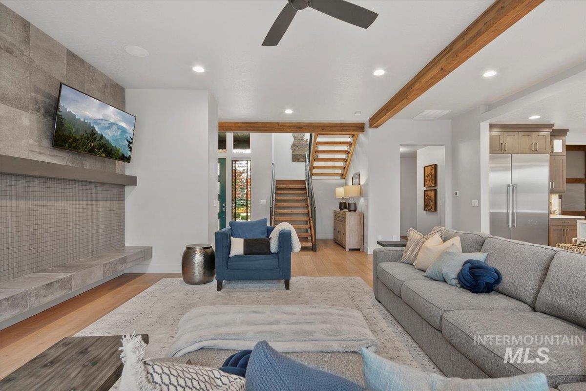 Living room with recessed lighting, beamed ceiling, stairway, light wood-style floors, and a ceiling fan