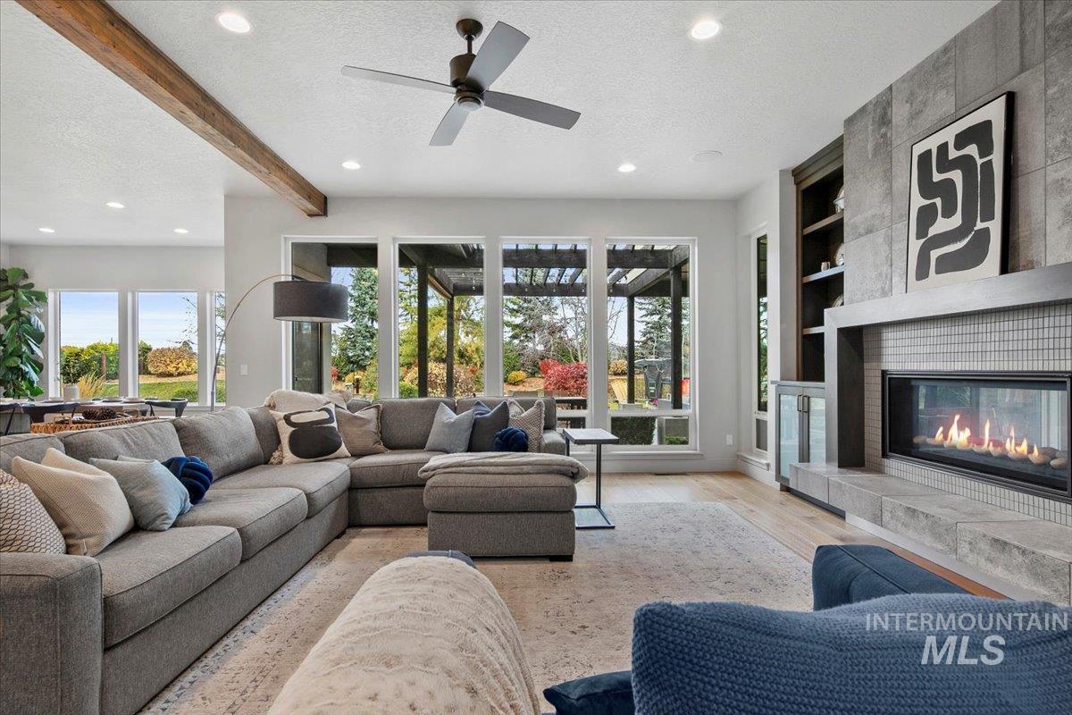 Living room featuring a textured ceiling, wood finished floors, recessed lighting, beam ceiling, and a tiled fireplace