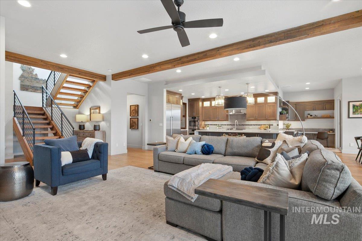 Living room featuring stairs, recessed lighting, beam ceiling, light wood-style flooring, and ceiling fan