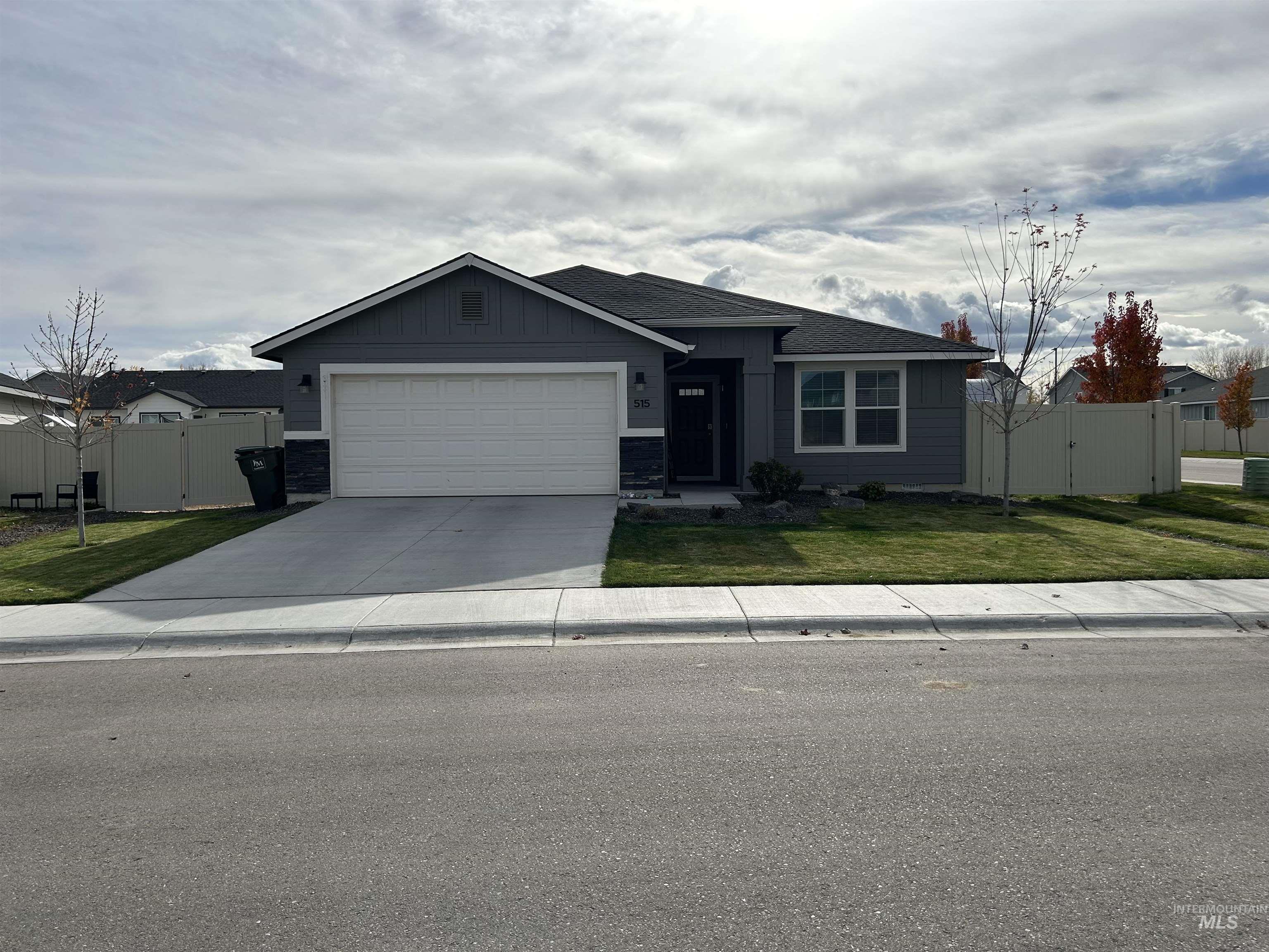 Ranch-style home with driveway, a garage, a gate, and board and batten siding