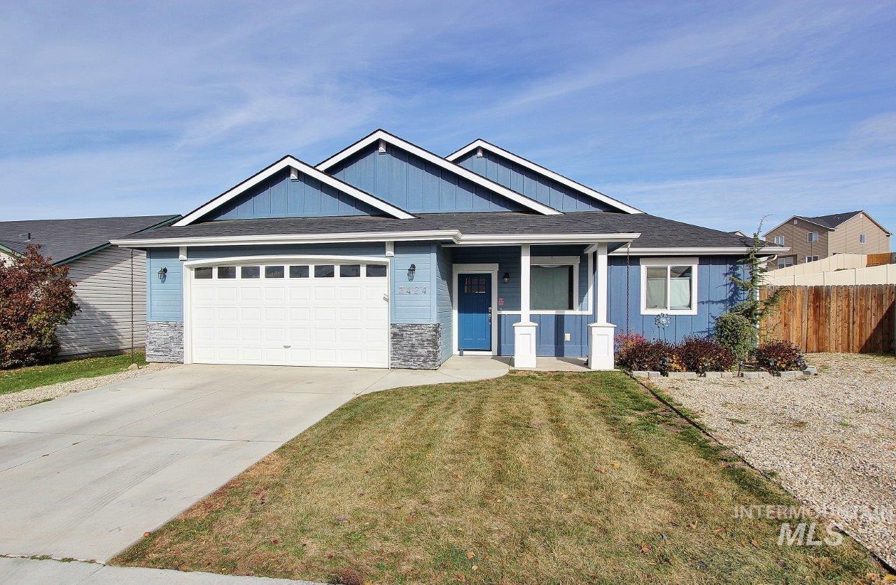 View of front facade with covered porch, board and batten siding, stone siding, driveway, and an attached garage