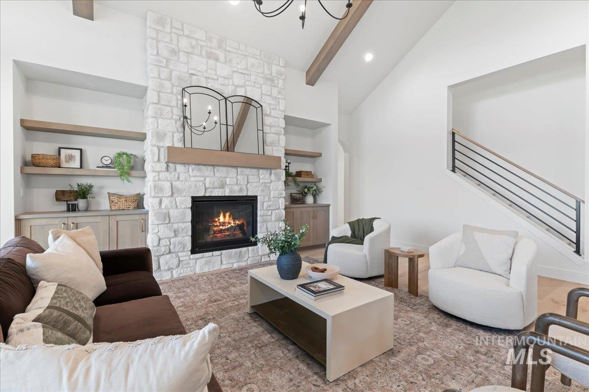 Living area with built in features, a fireplace, stairs, and a chandelier
