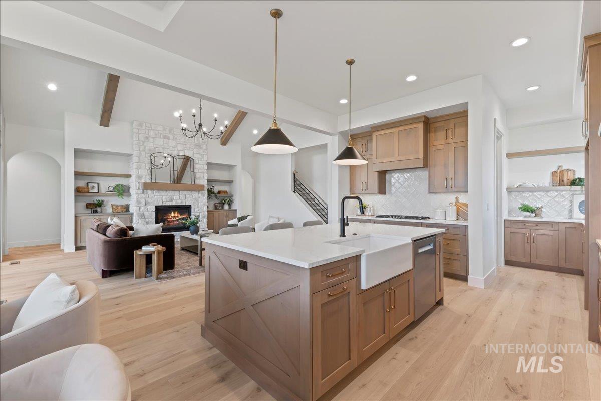 Kitchen featuring brown cabinets, light wood-style flooring, open floor plan, a fireplace, and recessed lighting