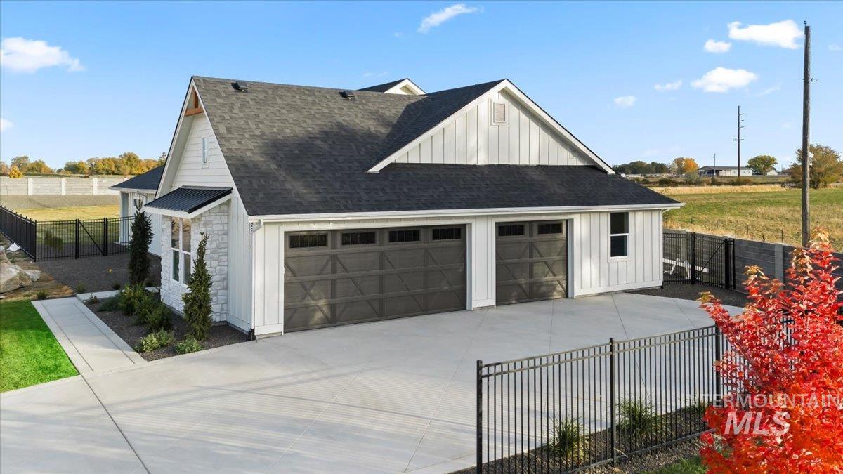 View of property exterior featuring board and batten siding, a shingled roof, and a garage