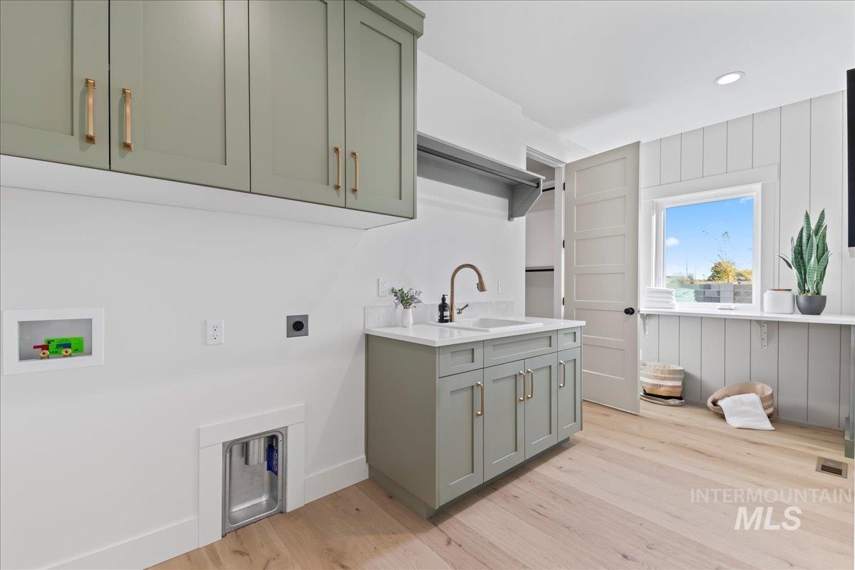 Laundry area featuring light wood-type flooring, cabinet space, electric dryer hookup, hookup for a washing machine, and recessed lighting