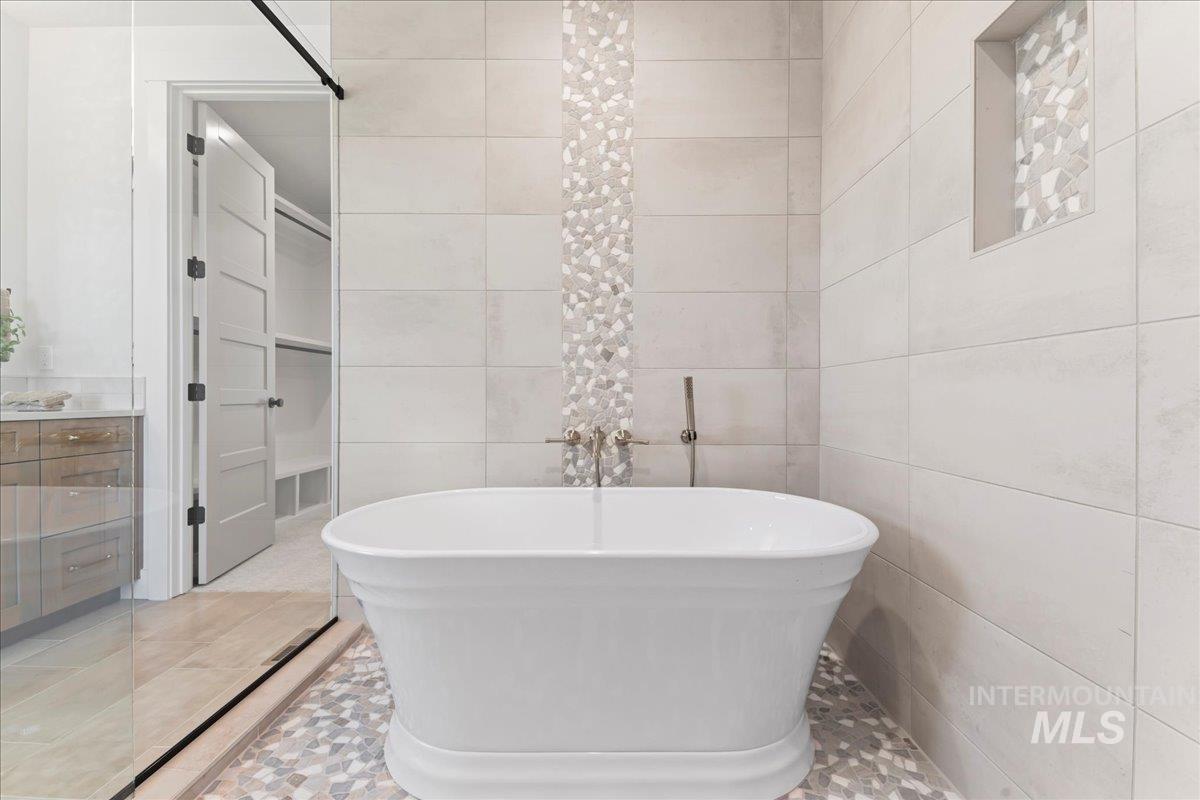 Bathroom with a soaking tub, tile walls, vanity, and tile patterned floors