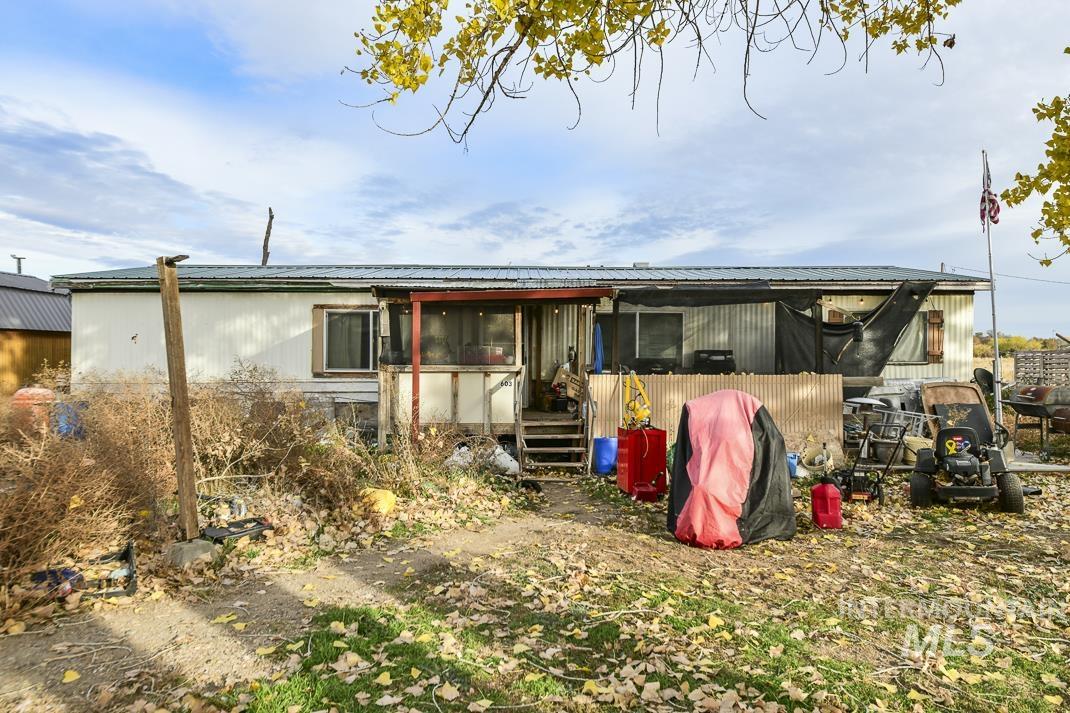 Back of house featuring a wooden deck, a metal roof, and a sunroom