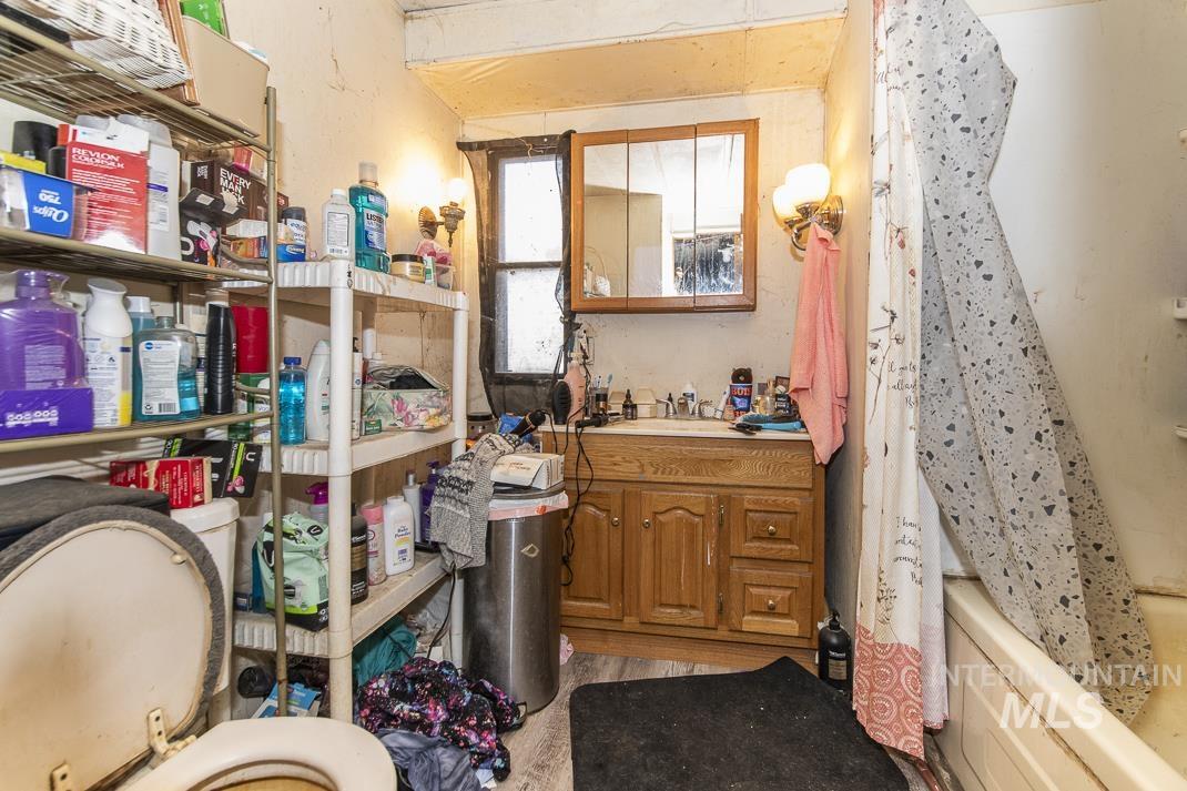Full bath with vanity, shower / bath combo with shower curtain, oil tank, and light wood-style floors
