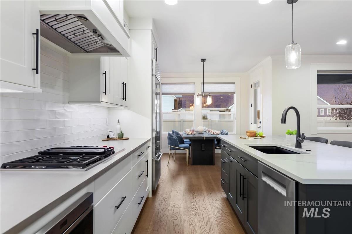 Kitchen with white cabinetry, premium range hood, decorative light fixtures, dark wood-style flooring, and recessed lighting