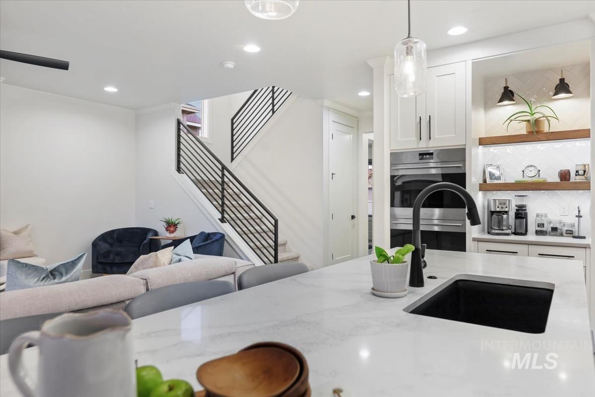 Kitchen featuring white cabinets, light stone counters, recessed lighting, open floor plan, and hanging light fixtures
