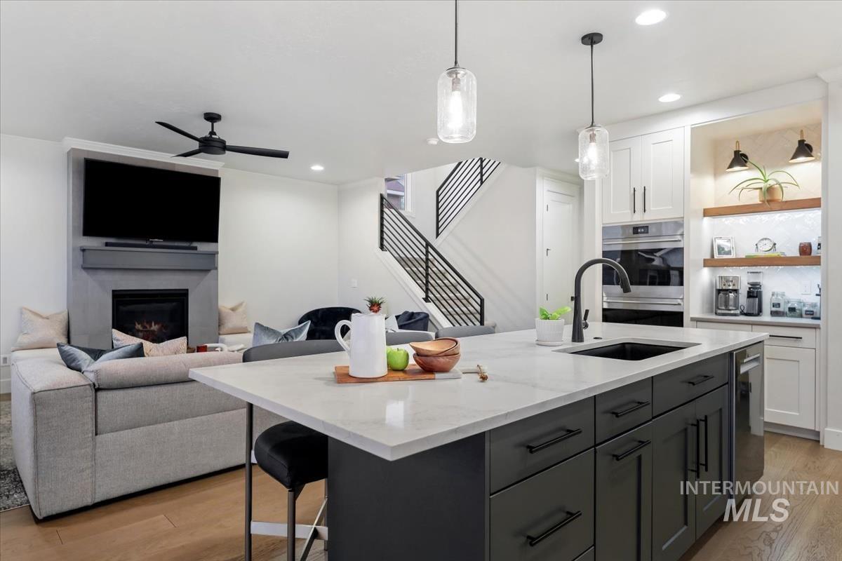Kitchen with white cabinets, light wood-type flooring, a breakfast bar area, an island with sink, and recessed lighting