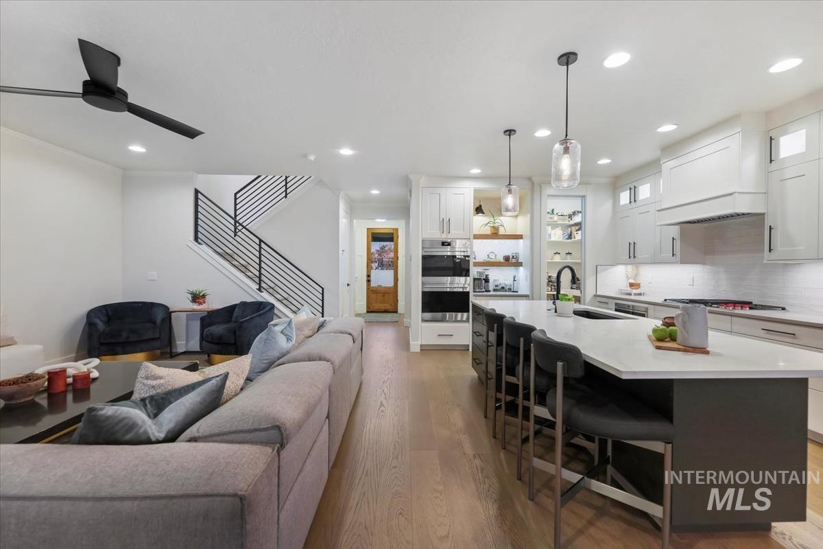 Living area with light wood finished floors, recessed lighting, stairway, and ceiling fan