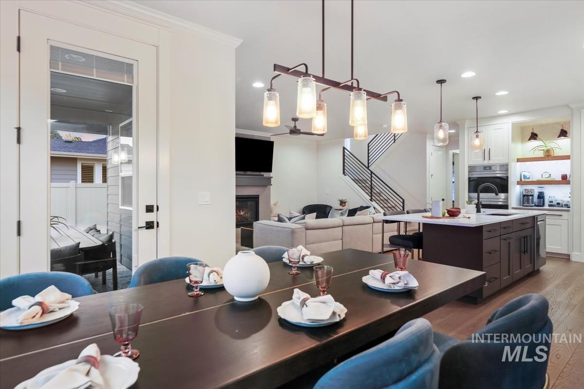 Dining room featuring a glass covered fireplace, light wood-style floors, stairway, and recessed lighting