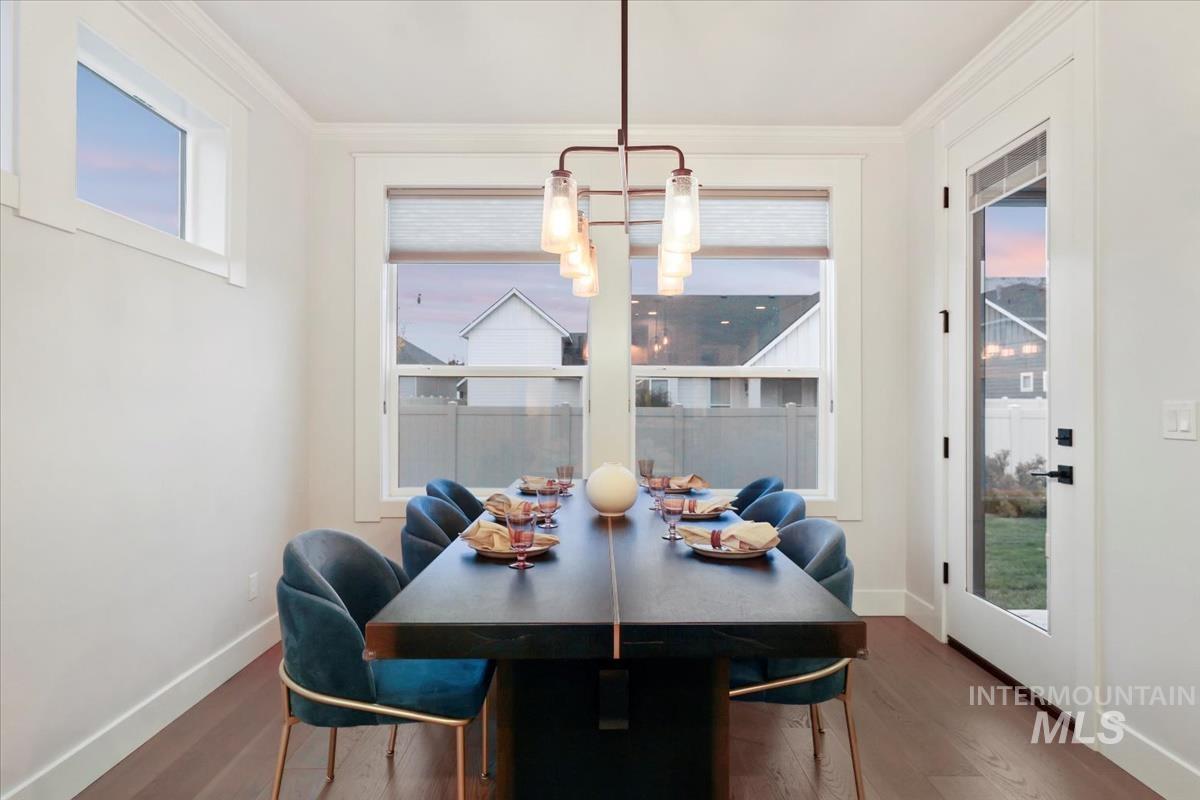 Dining room featuring wood finished floors, ornamental molding, and a chandelier