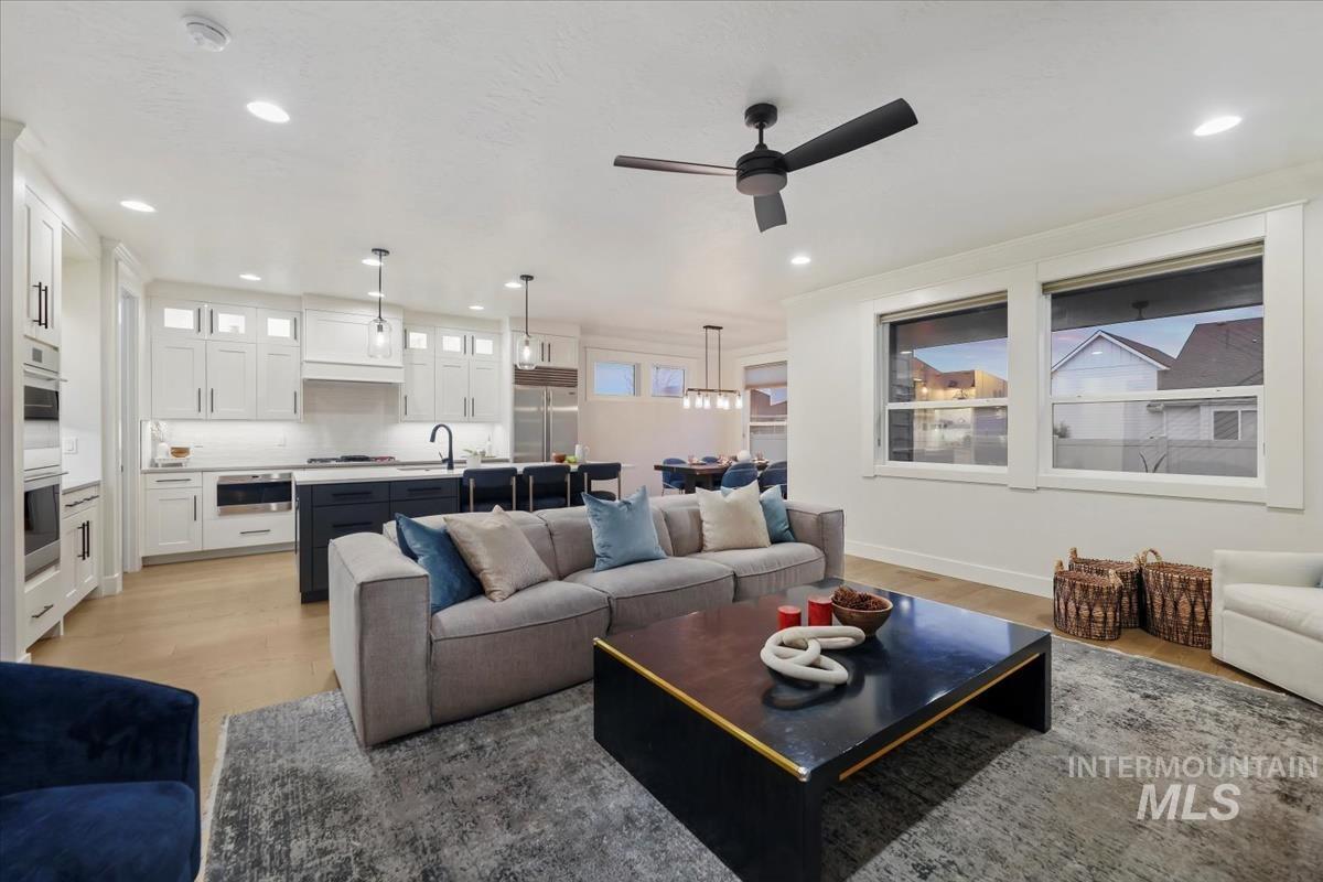 Living area with light wood-style flooring, a ceiling fan, and recessed lighting