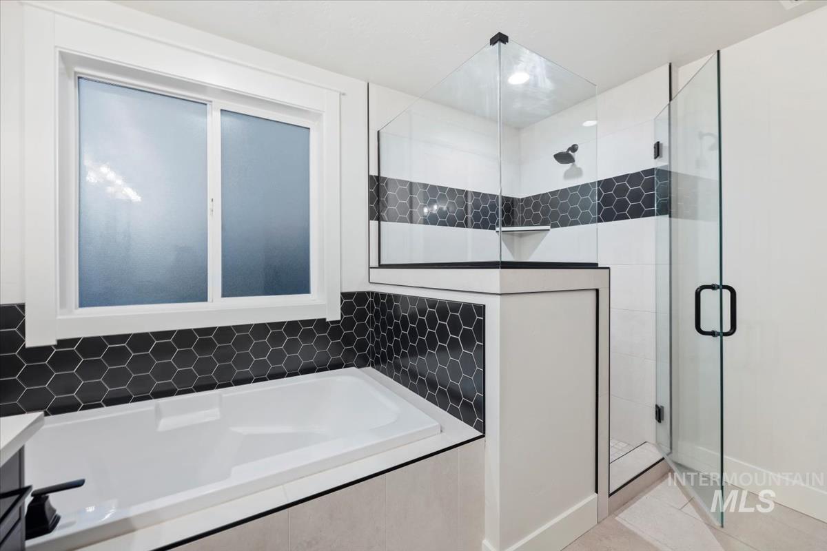 Bathroom featuring a garden tub, a stall shower, and light tile patterned floors