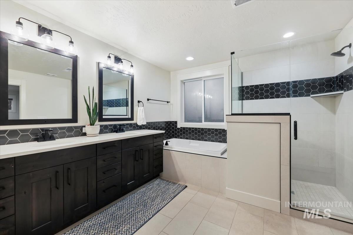 Full bathroom with double vanity, light tile patterned floors, a garden tub, a shower stall, and recessed lighting