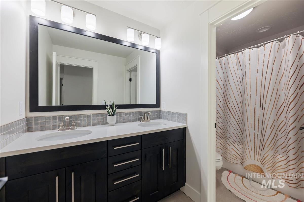 Bathroom featuring double vanity, tasteful backsplash, and shower / bath combo