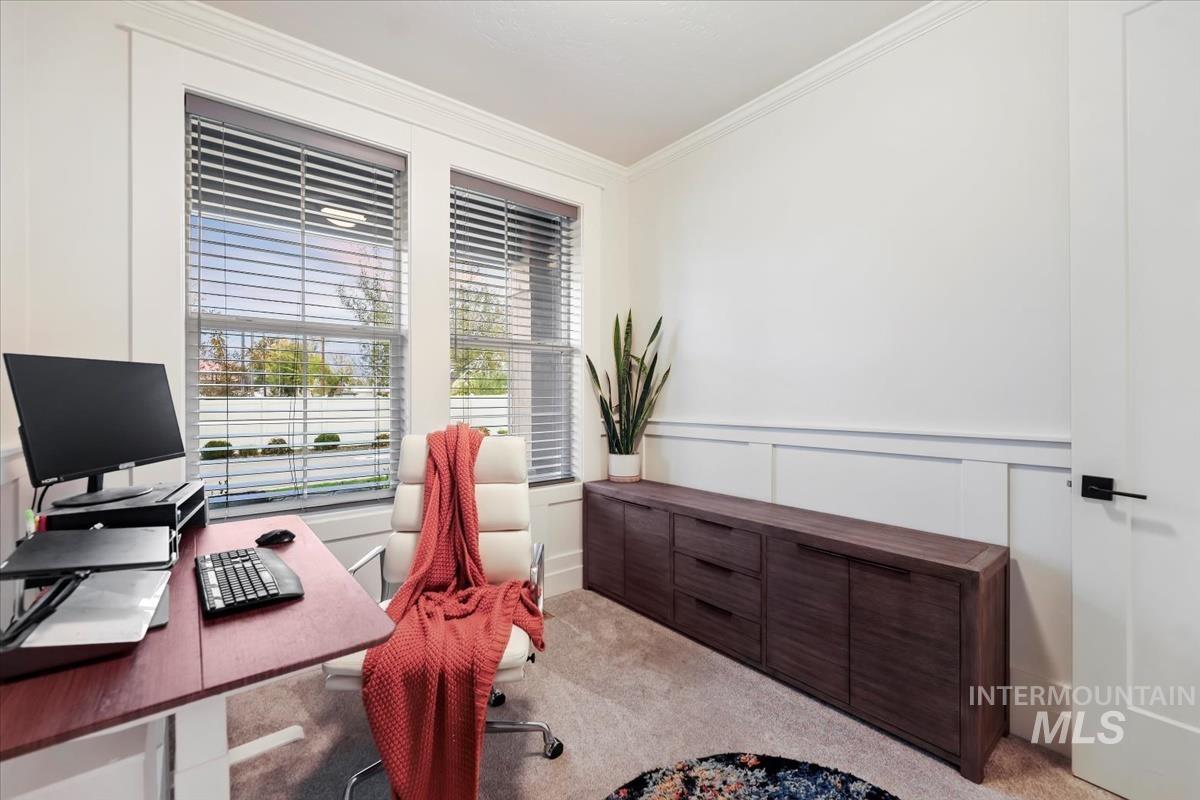 Carpeted home office with crown molding and a decorative wall