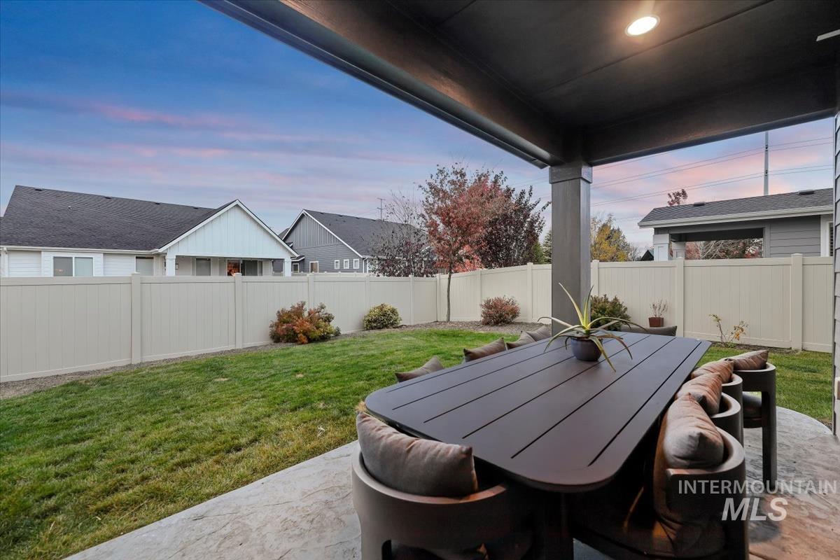 Patio terrace at dusk featuring a fenced backyard, outdoor dining area, a patio, and a residential view