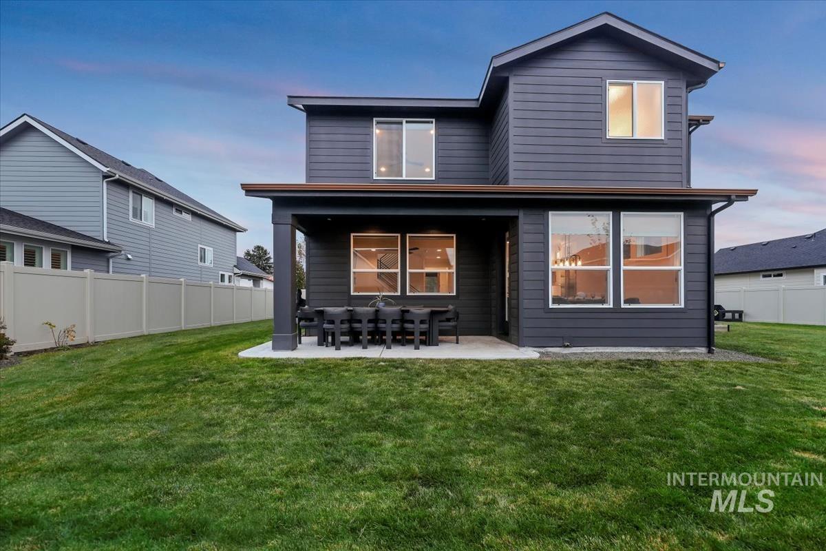 Back of house at dusk with a fenced backyard and a patio area