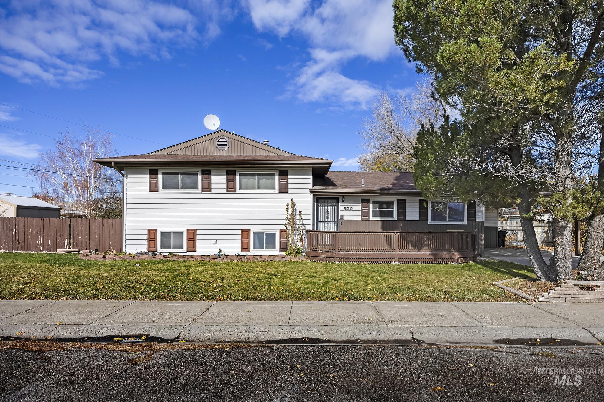 View of front facade with a wooden deck and roof with shingles