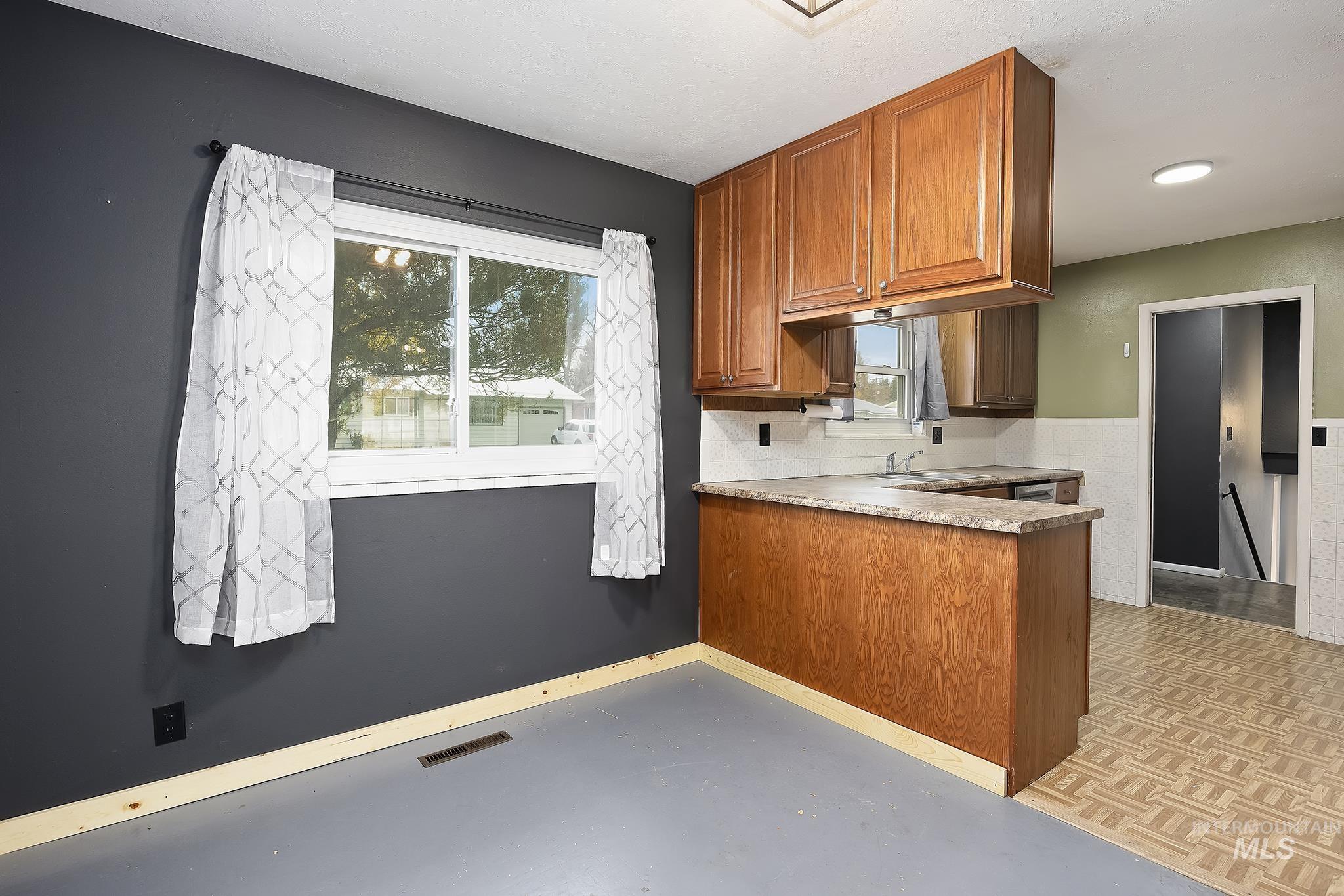 Kitchen with brown cabinets, light countertops, a peninsula, and tasteful backsplash