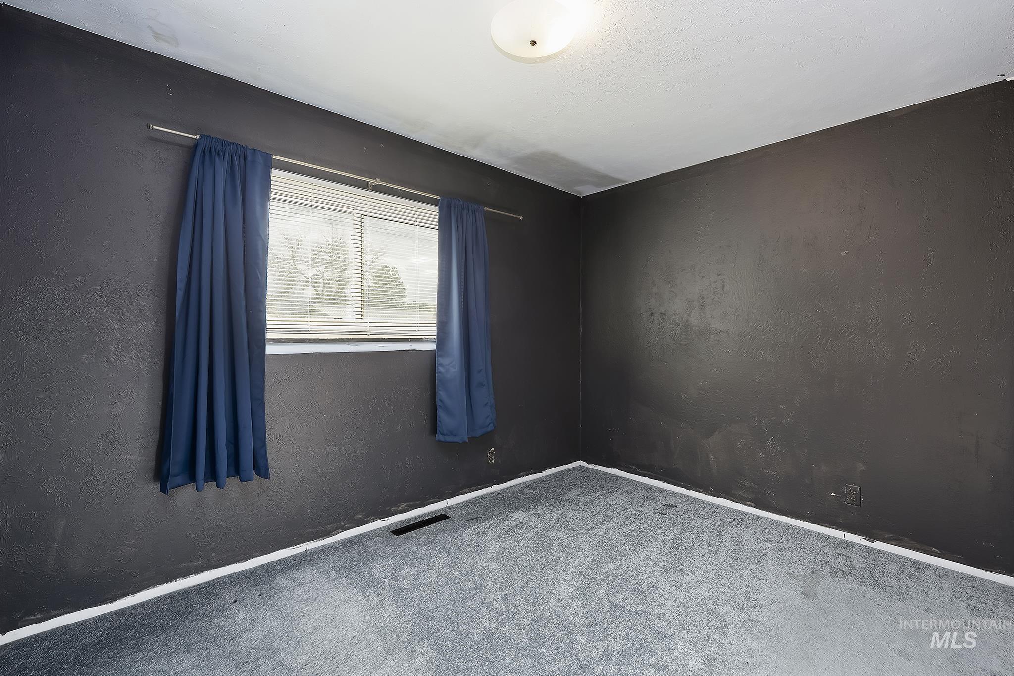Carpeted empty room featuring a textured wall and baseboards