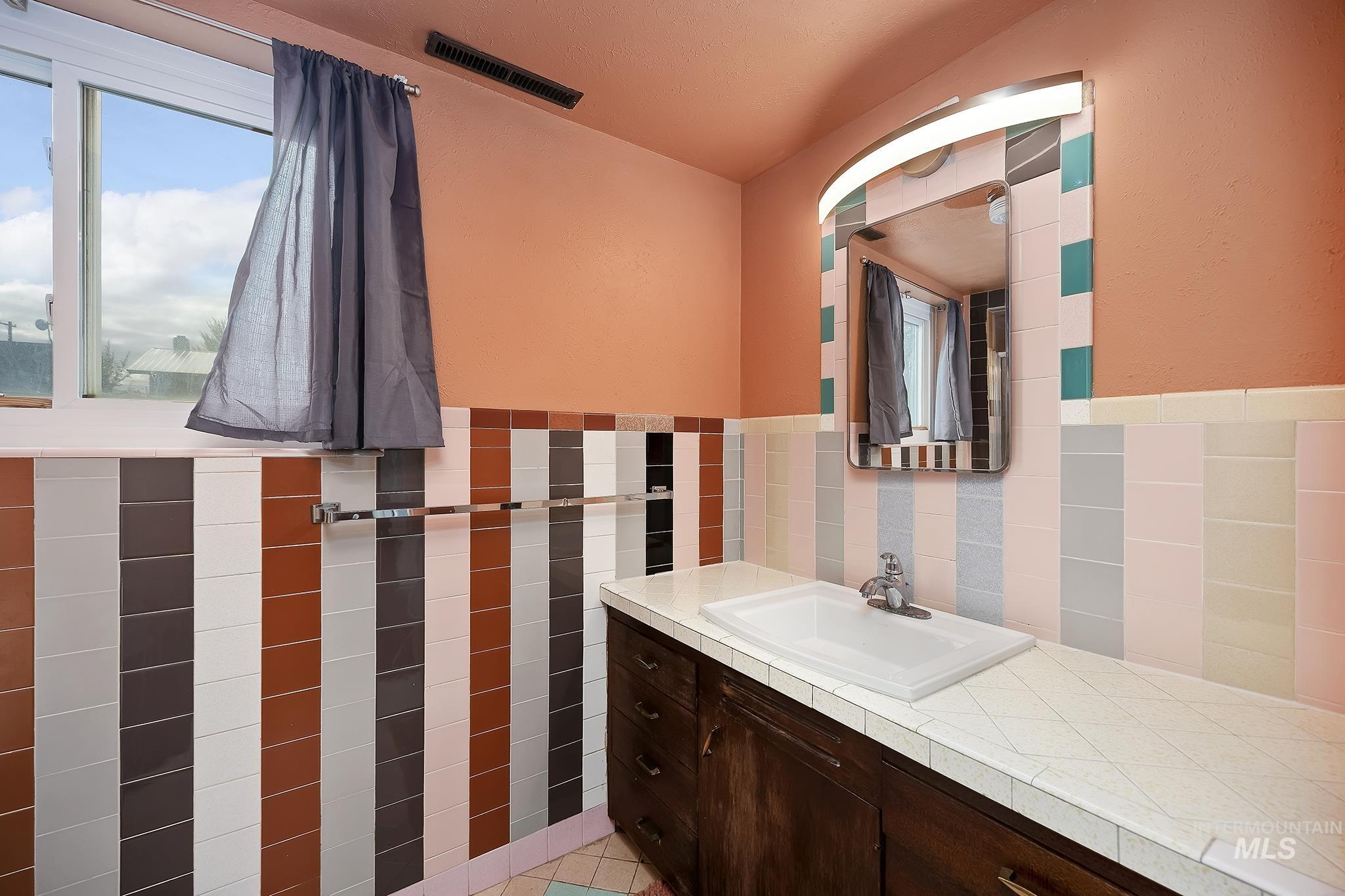 Bathroom with tile walls, vanity, light tile patterned floors, and wainscoting