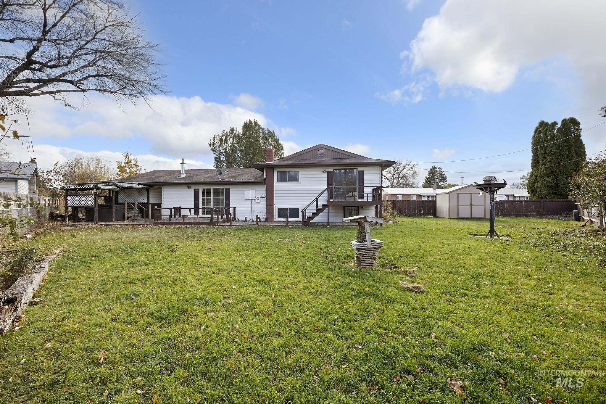 Back of property featuring a fenced backyard, a storage unit, stairway, and a patio