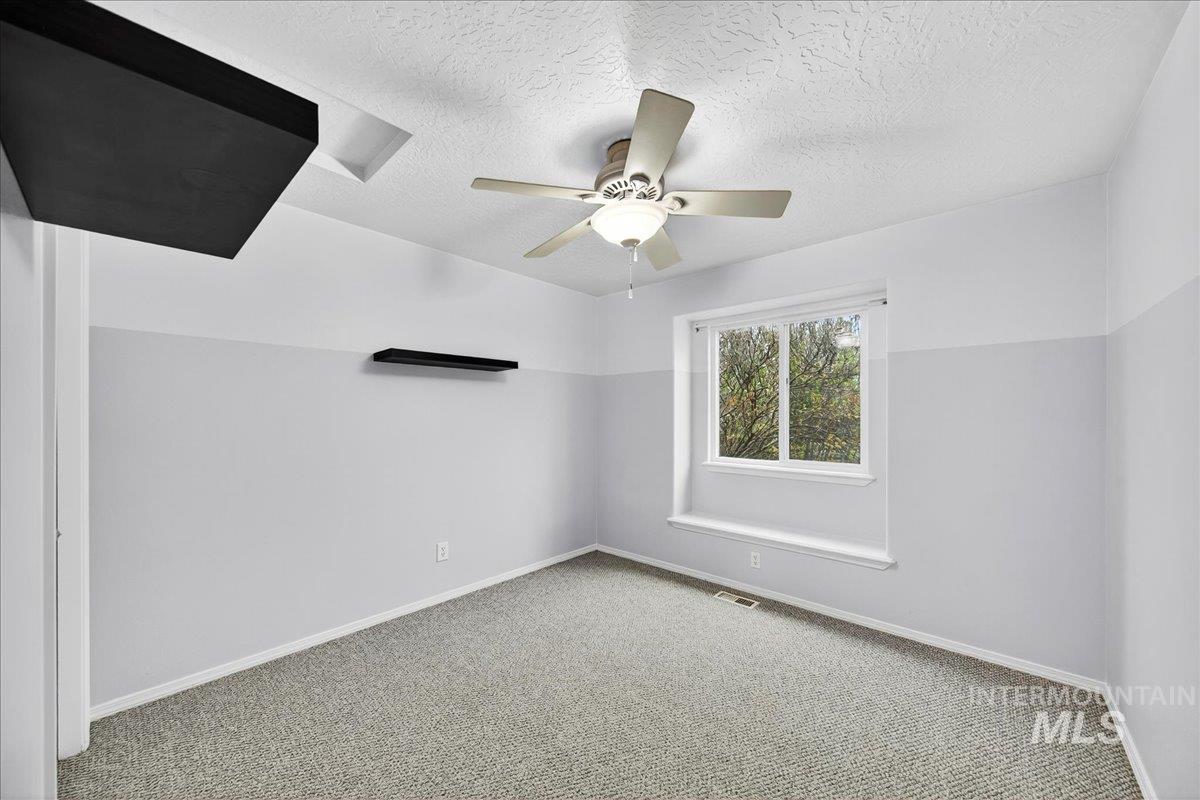Carpeted spare room featuring a textured ceiling and ceiling fan