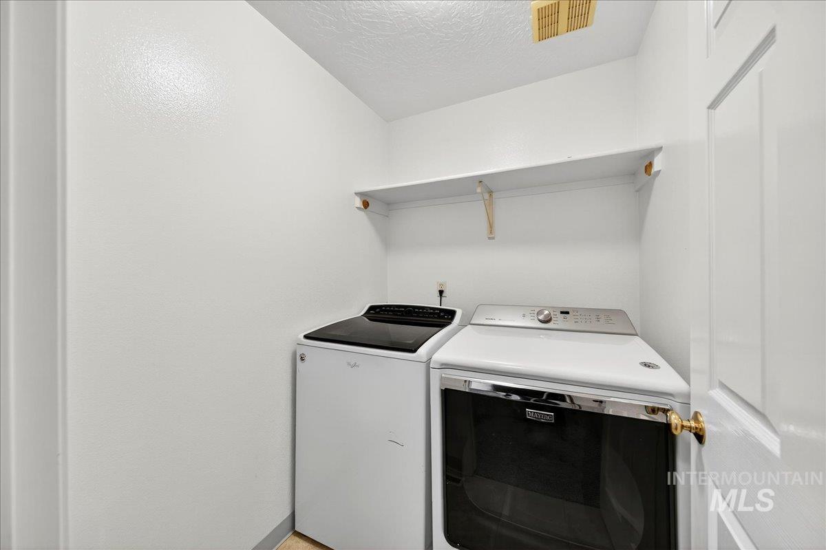 Laundry room featuring washing machine and clothes dryer and a textured ceiling