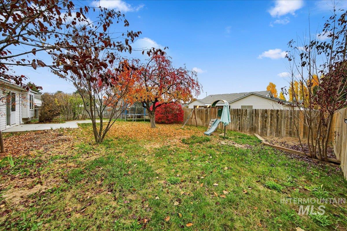 Fenced backyard featuring a trampoline