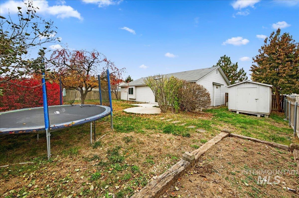 Fenced backyard with a storage shed, a patio, and a trampoline