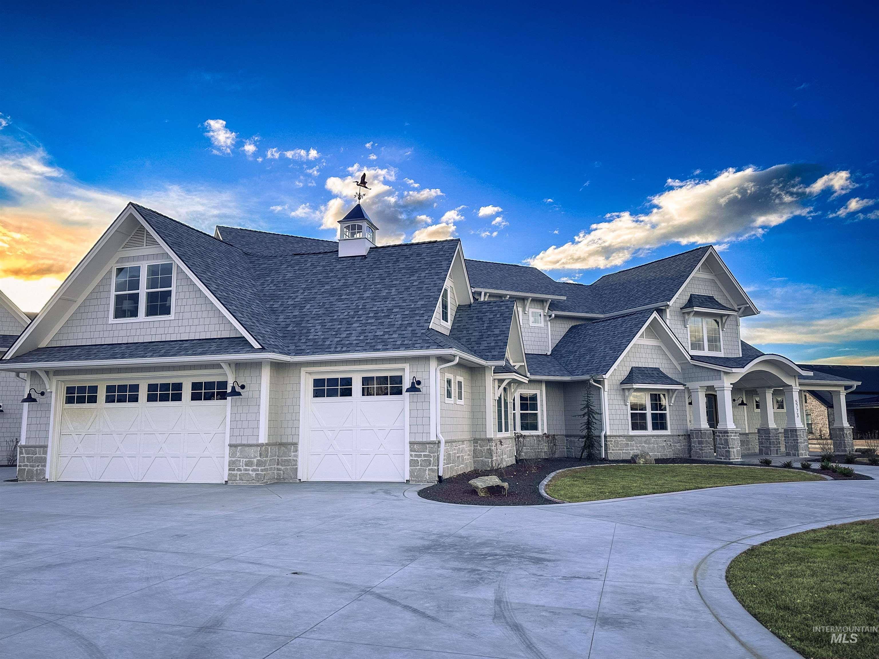 View of front of home with concrete driveway, stone siding, a shingled roof, and a front yard