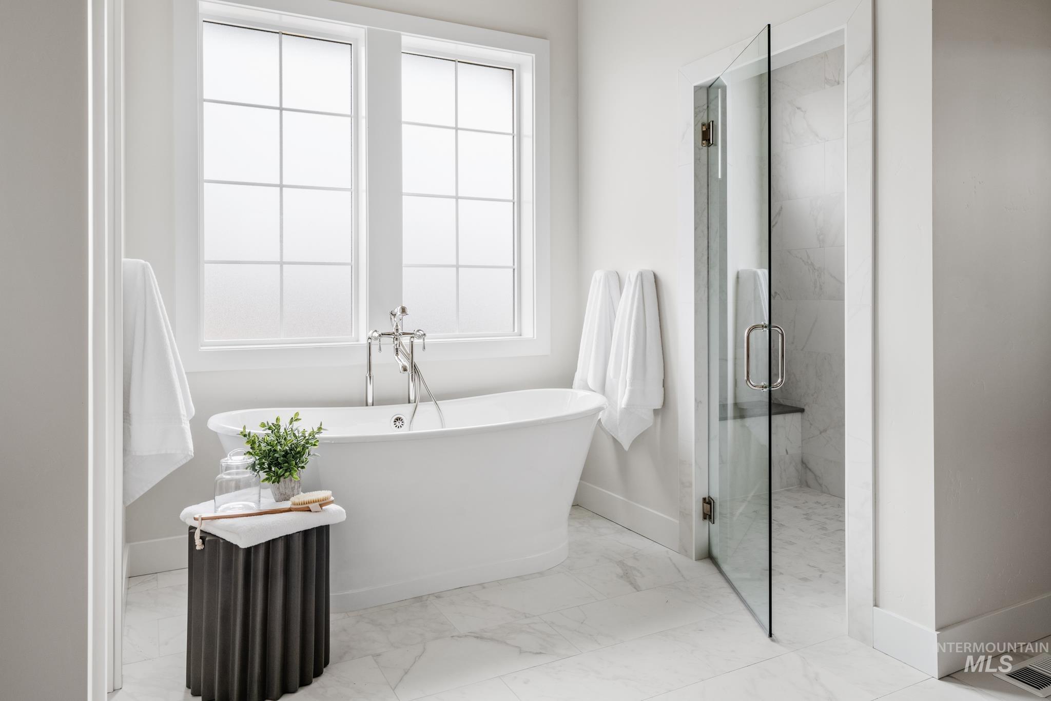 Full bathroom with a marble finish shower, light marble finish flooring, and a freestanding bath