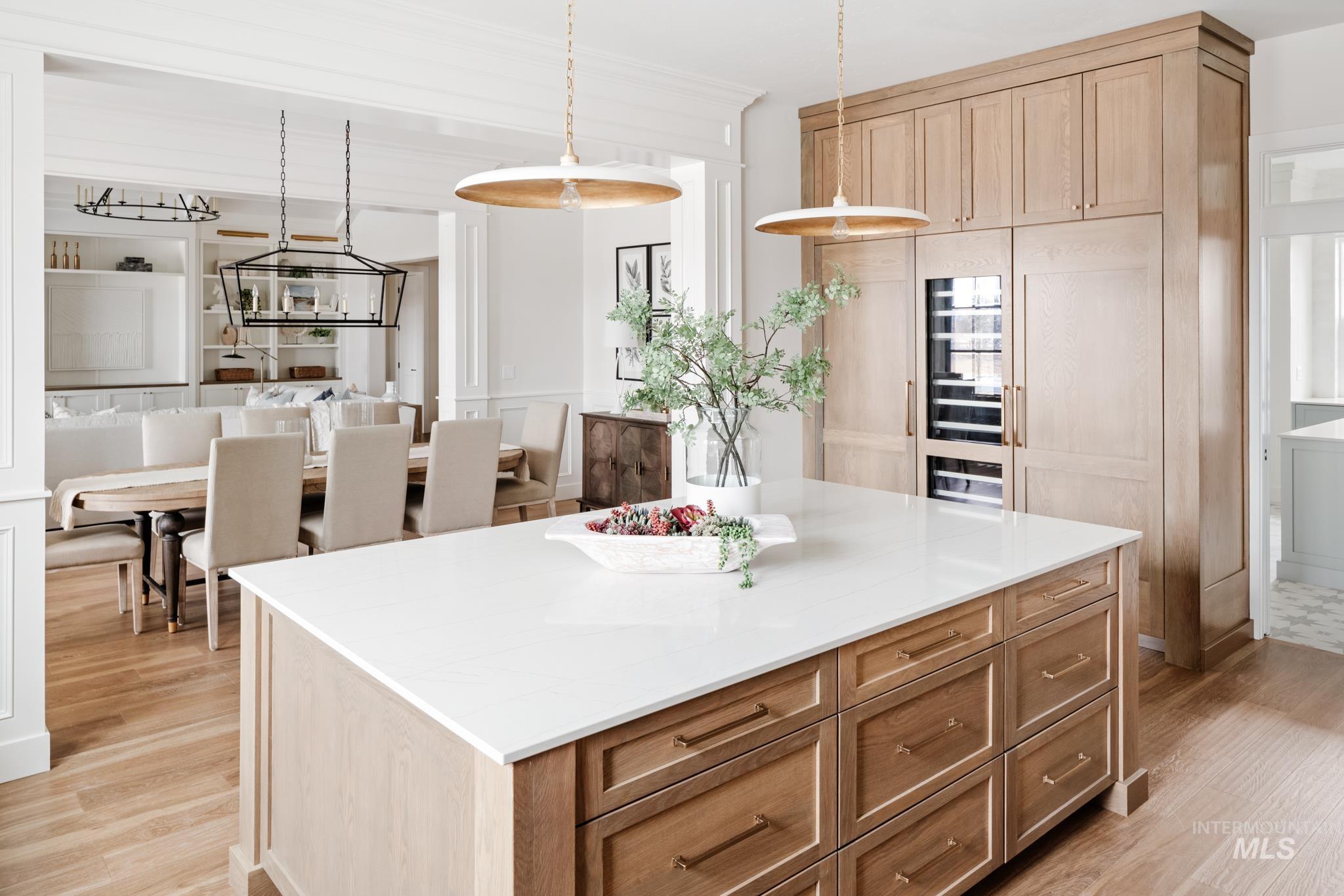 Kitchen with a kitchen island, hanging light fixtures, light wood-style floors, light brown cabinetry, and light stone countertops