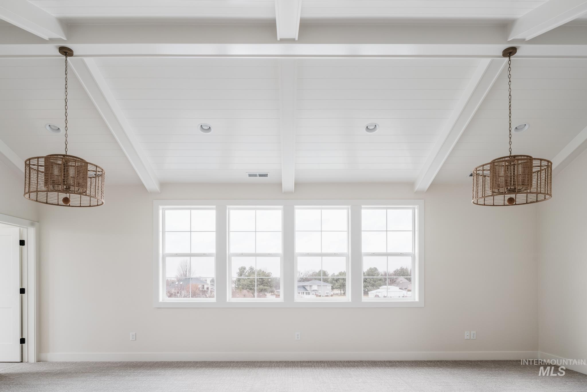 Carpeted spare room featuring a chandelier and beam ceiling
