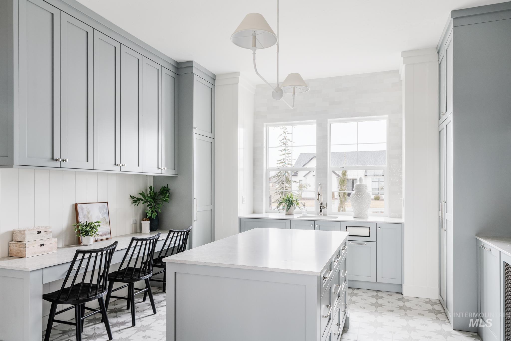 Kitchen with gray cabinets, decorative light fixtures, light flooring, and a center island