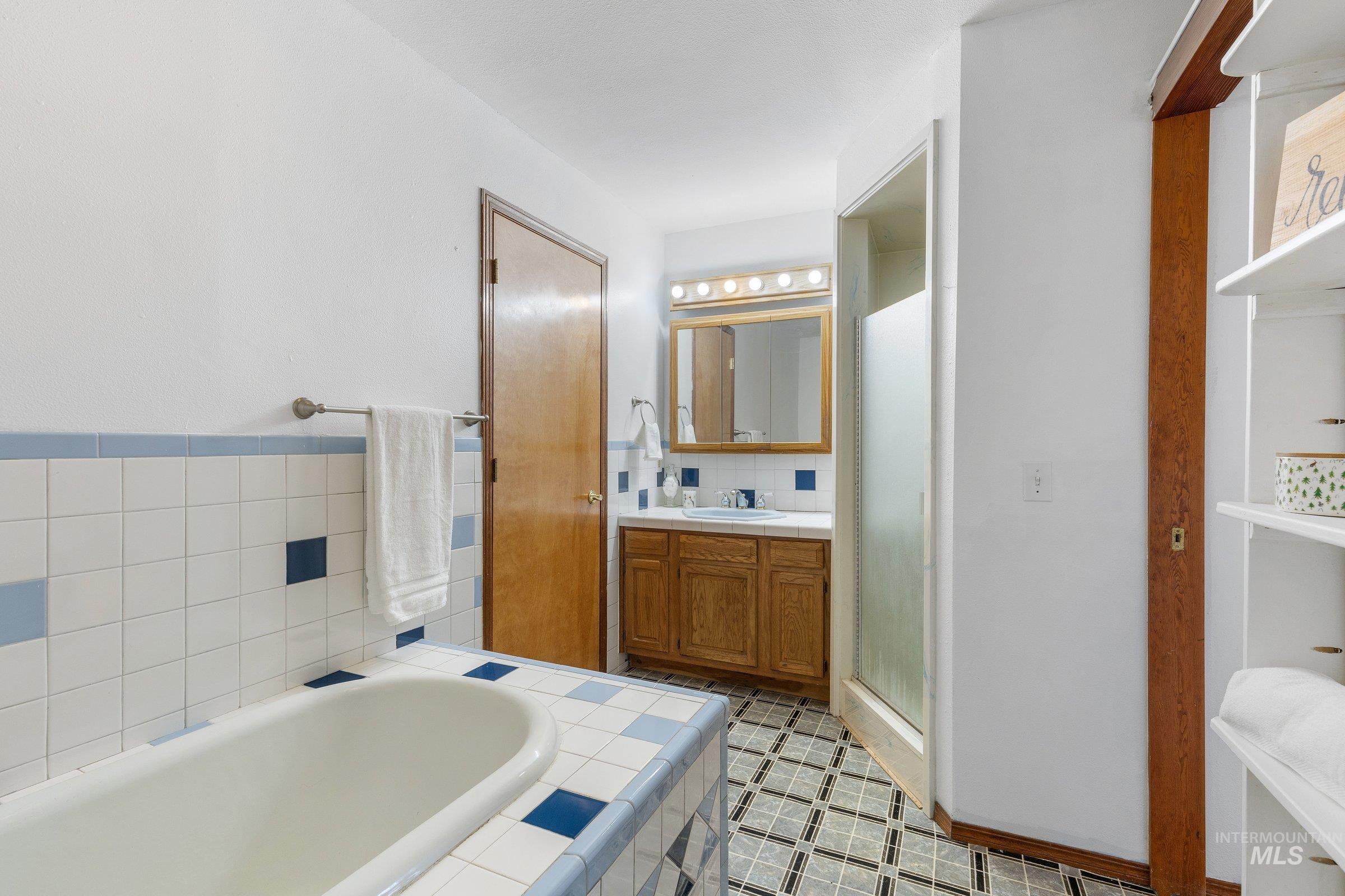 Full bathroom with vanity, a bath, and a shower stall