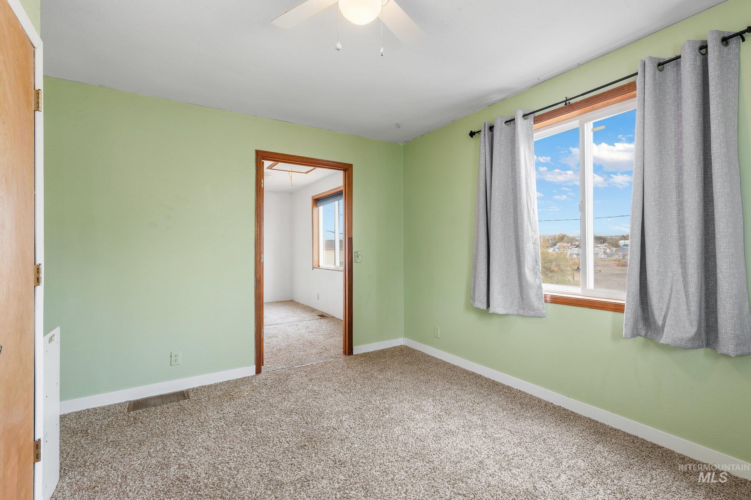 Unfurnished room with carpet floors, plenty of natural light, and ceiling fan