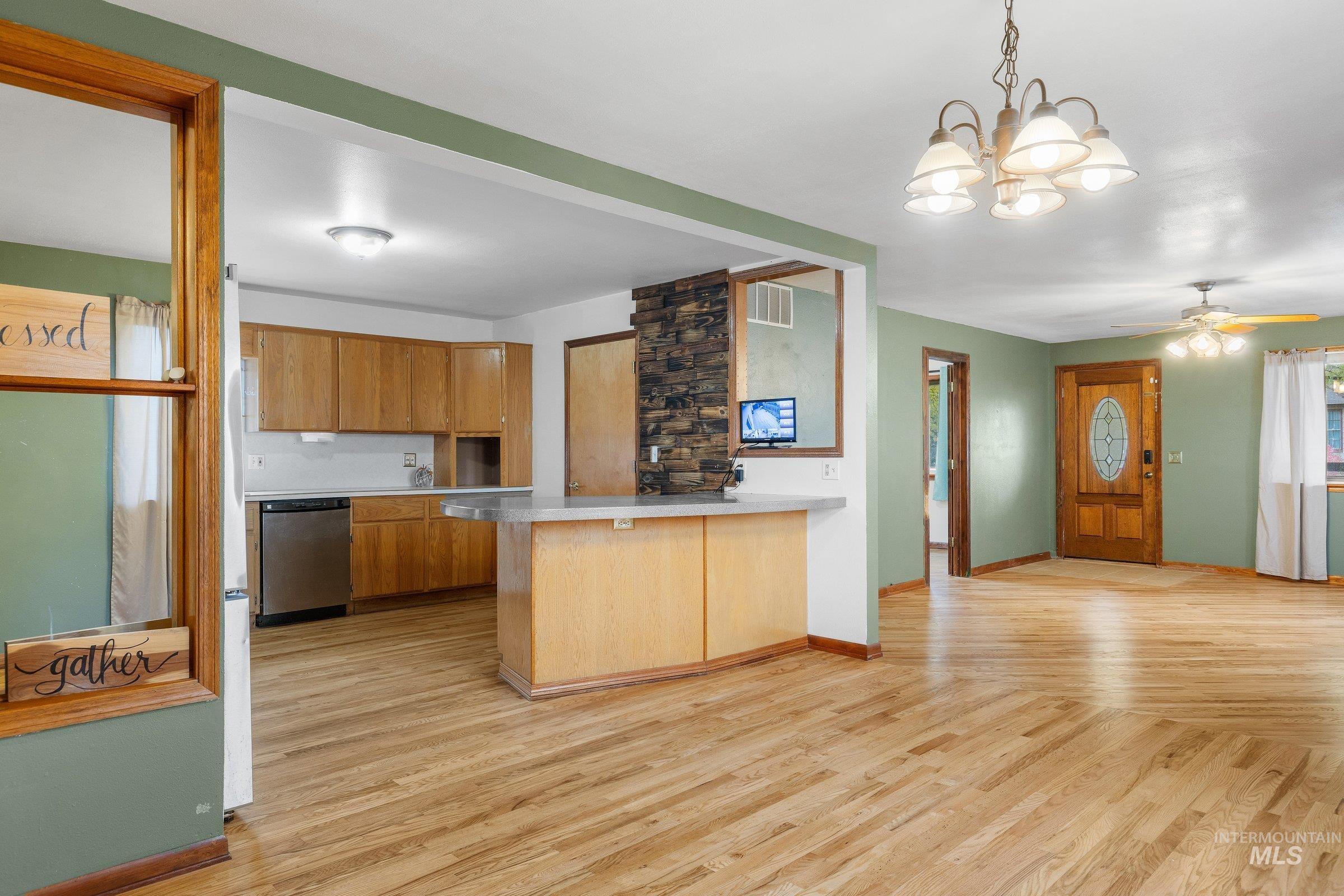 Kitchen with a peninsula, light wood finished floors, pendant lighting, and light countertops