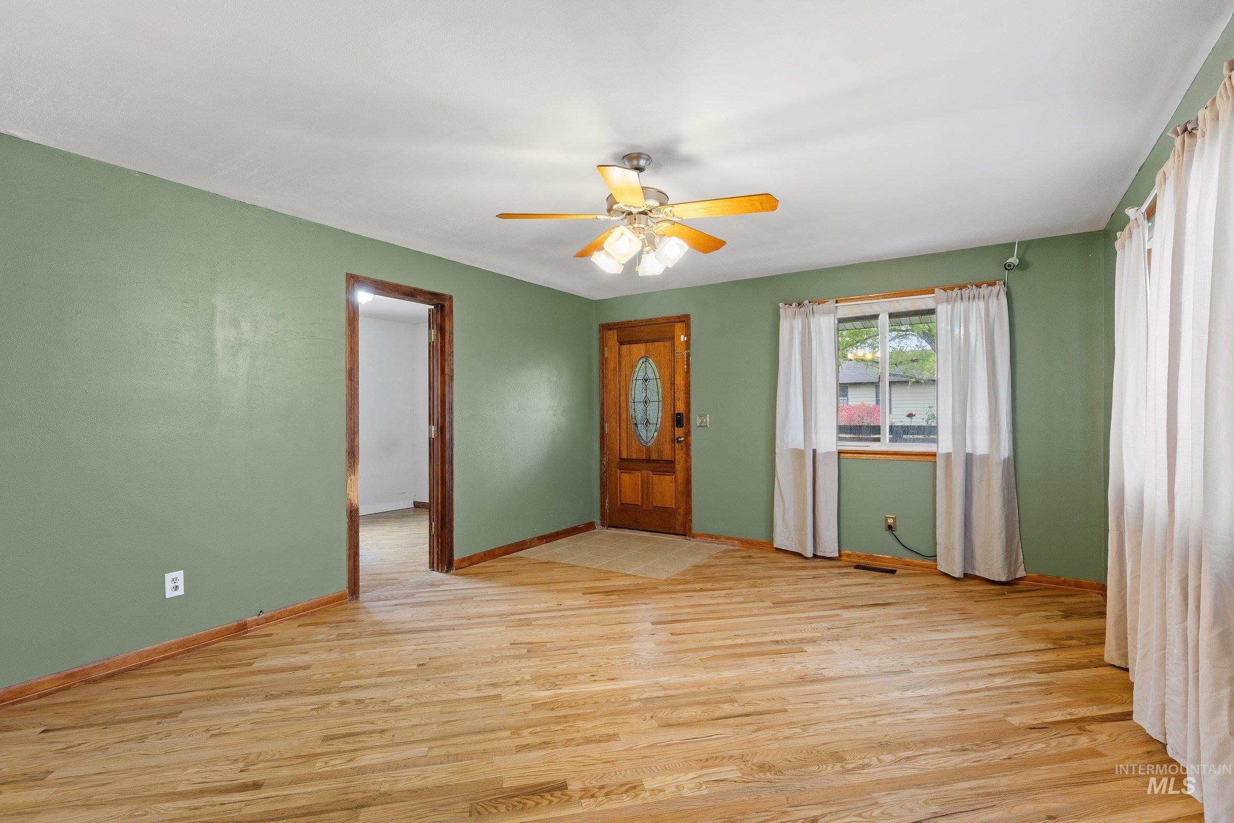 Empty room featuring light wood-type flooring and a ceiling fan