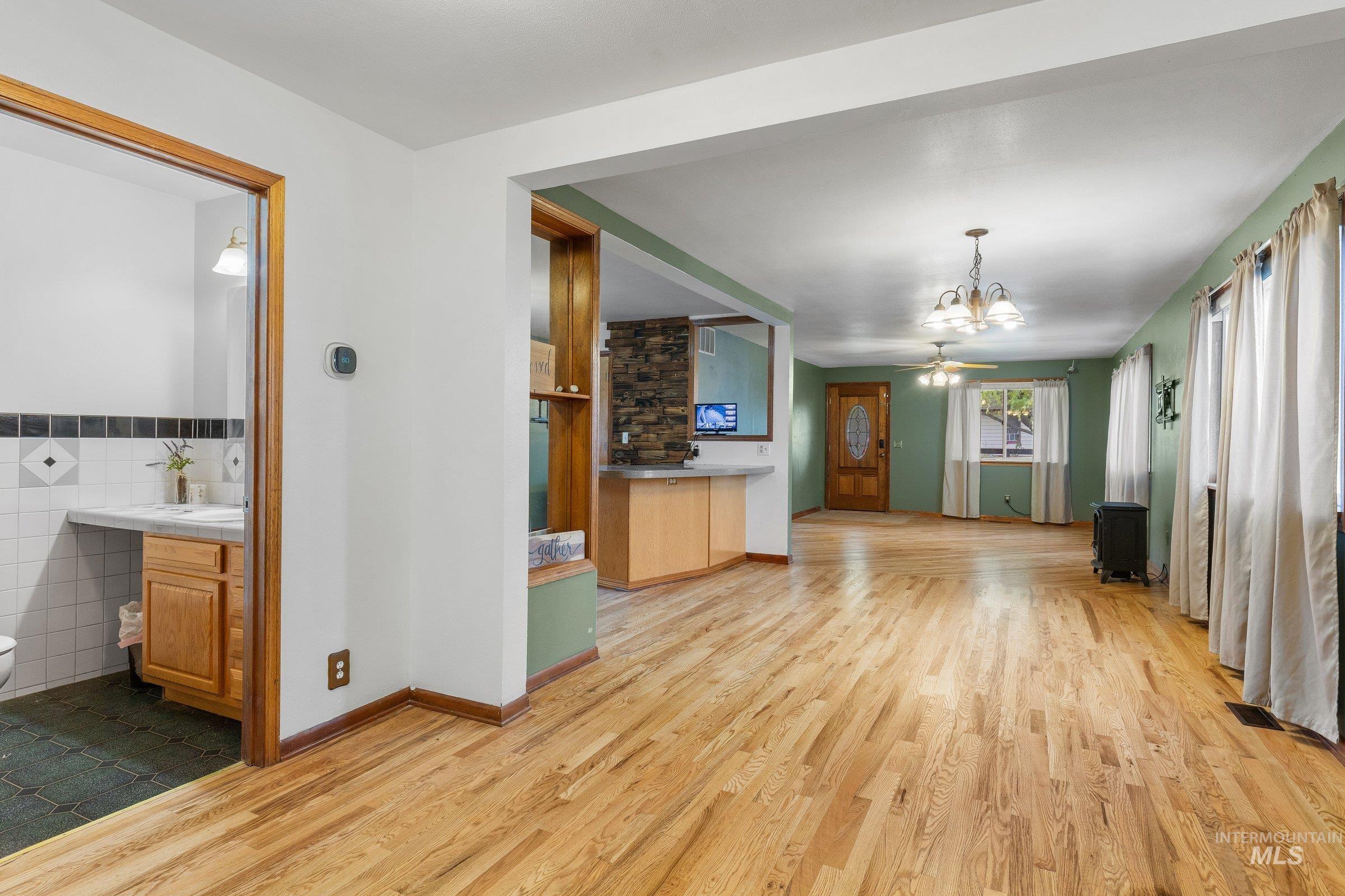 Unfurnished living room featuring light wood-style flooring, a chandelier, and tile walls
