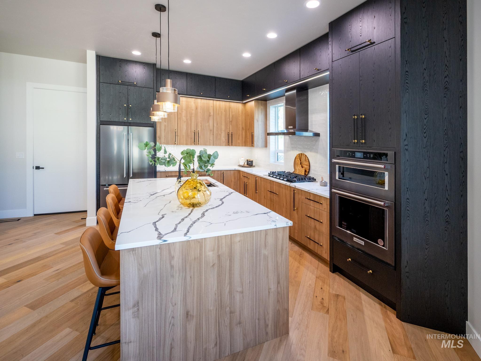 Kitchen featuring a breakfast bar area, light stone countertops, hanging light fixtures, appliances with stainless steel finishes, and a kitchen island