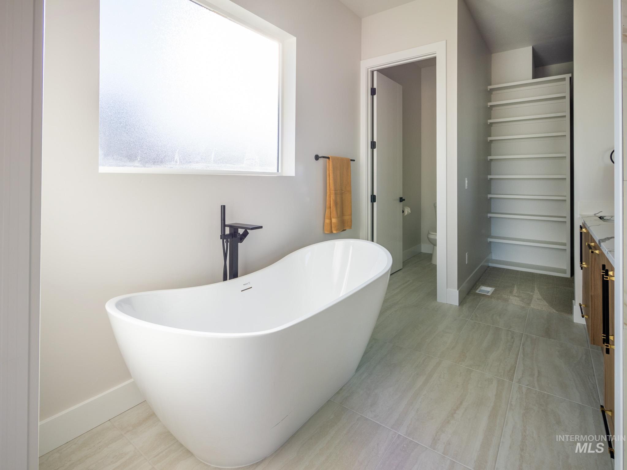 Bathroom with a soaking tub, light tile patterned flooring, and vanity