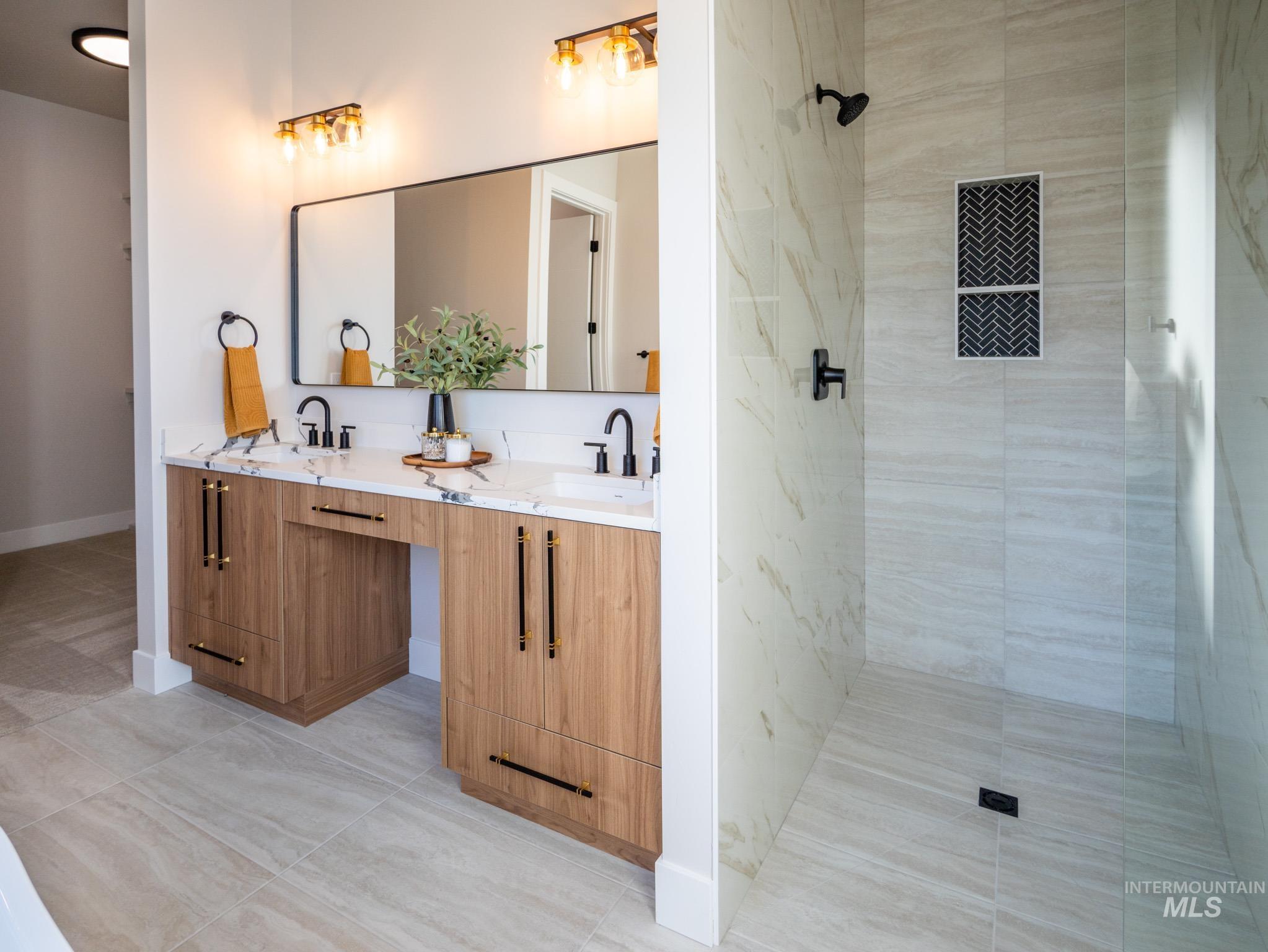 Bathroom with double vanity, light tile patterned flooring, and tiled shower